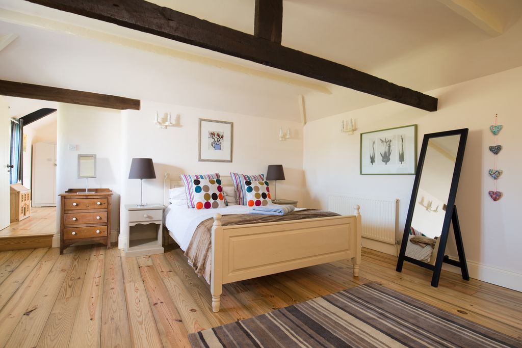 Large master bedroom with wooden beams across the ceiling