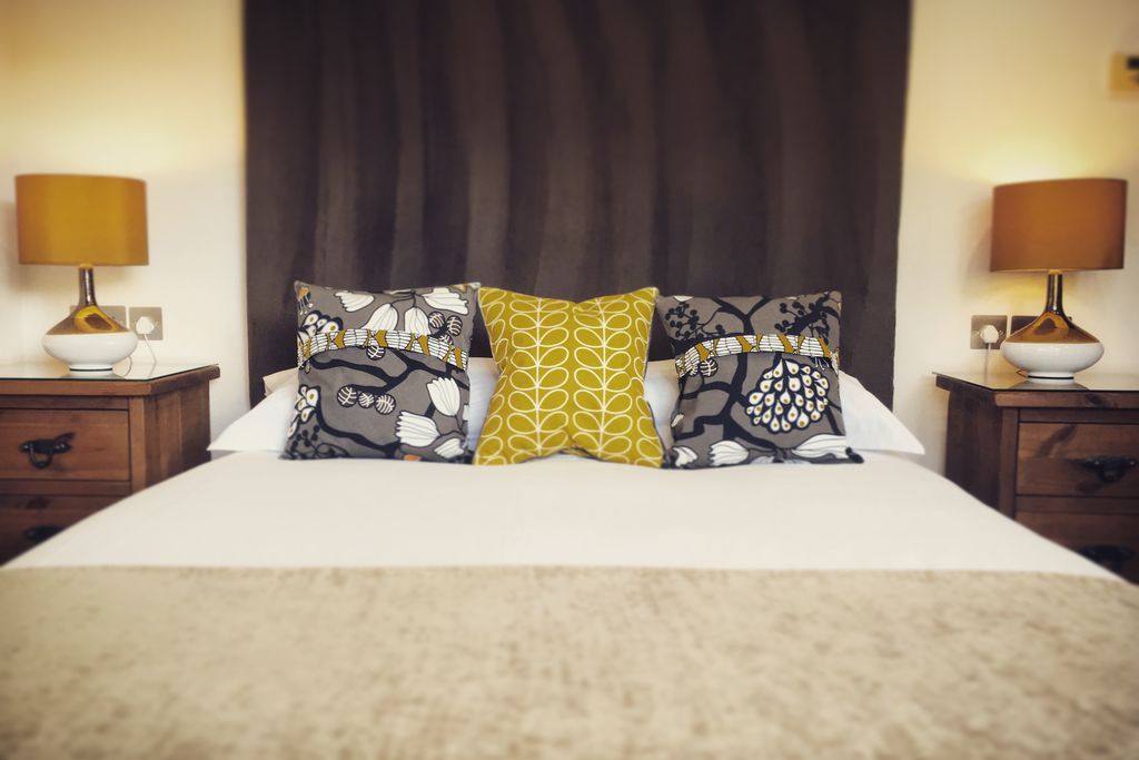 Minimalist style double bedroom with brightly coloured cushions on the bed
