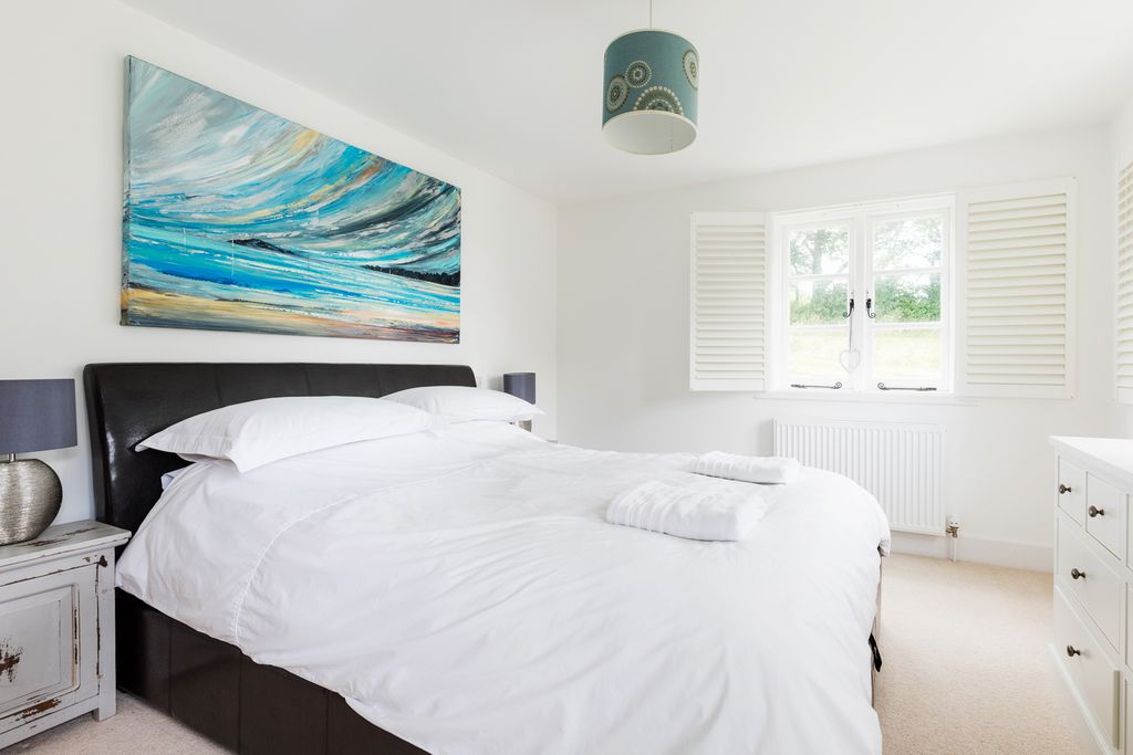 Naturally lit master bedroom with double bed and stylish furniture