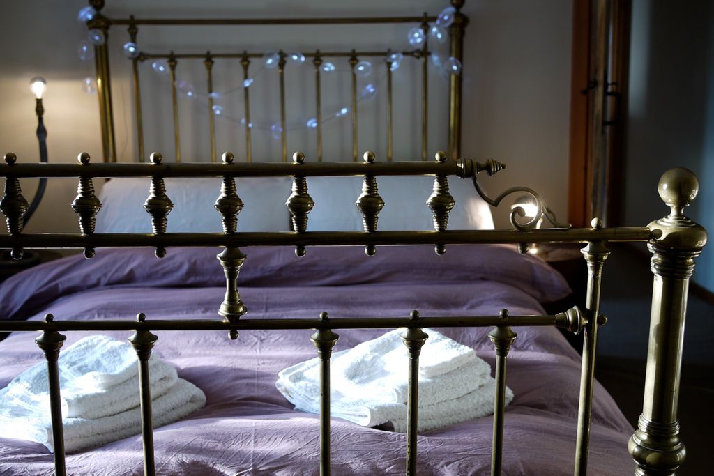 Double bedroom with fresh linen on a wrought iron bedstead with fairy lights on the bedhead