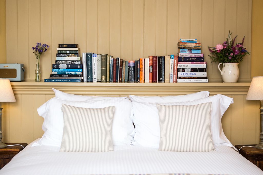 Double beds with bedside tables and books on a shelf above the headboard