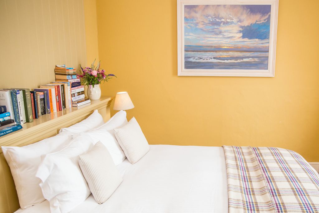 Double bed with painting on the wall at The Old Coastguard