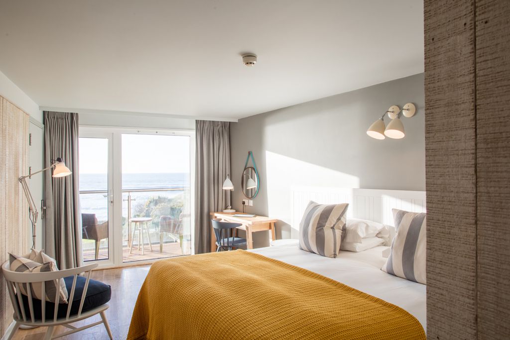 Stylish double bedroom with doors out to a balcony with seating and sea views