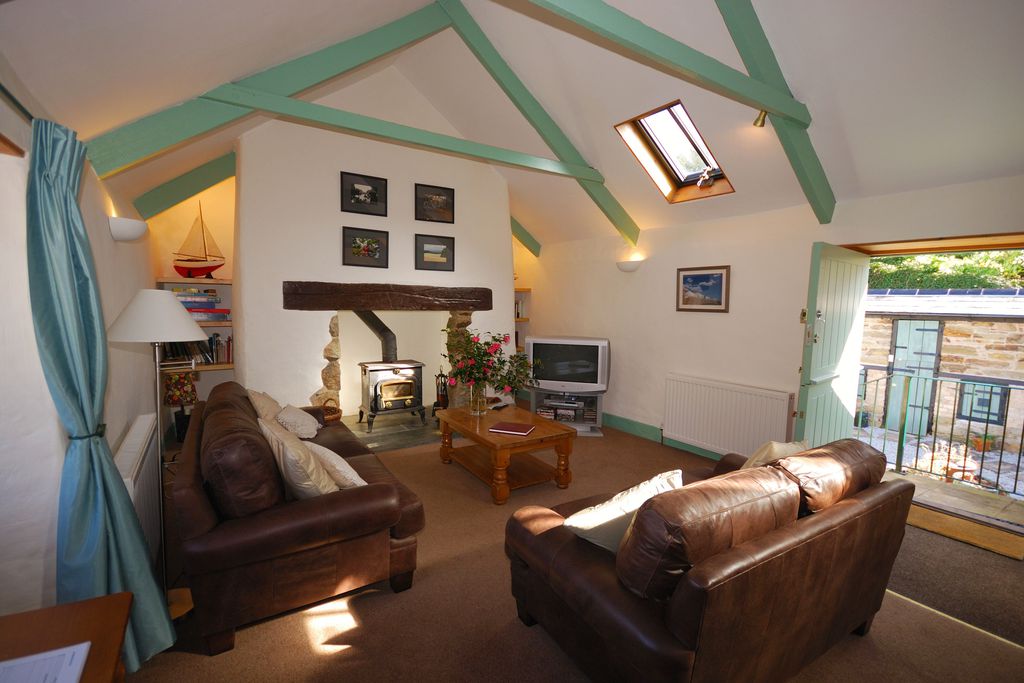 Lounge area with leather sofas, exposed beams and wooden doors swung open leading onto the balcony