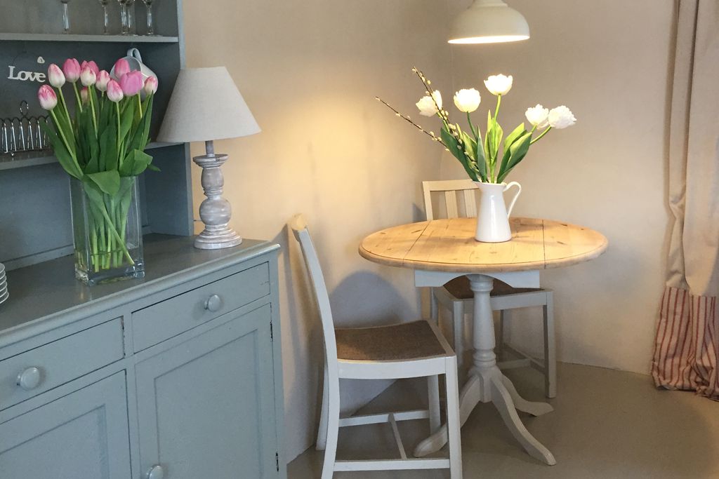 Country cottage style dining area with table for two and tulips in a vase