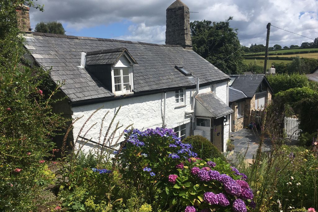 Exterior of Stares Nest in Devon with private entrance through white picket gate and a lovely garden