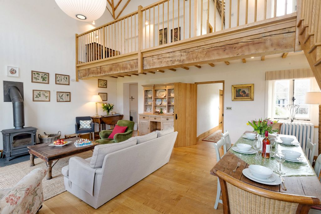 Bright and spacious living area with wood burner and view of upstairs mezzanine area at The Dairy at Collfryn Farm in Powys, Wales.