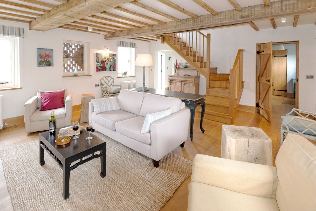 Light and spacious living area with exposed beams and neutral furniture at Field House, Collfryn Farm in Powys, Wales