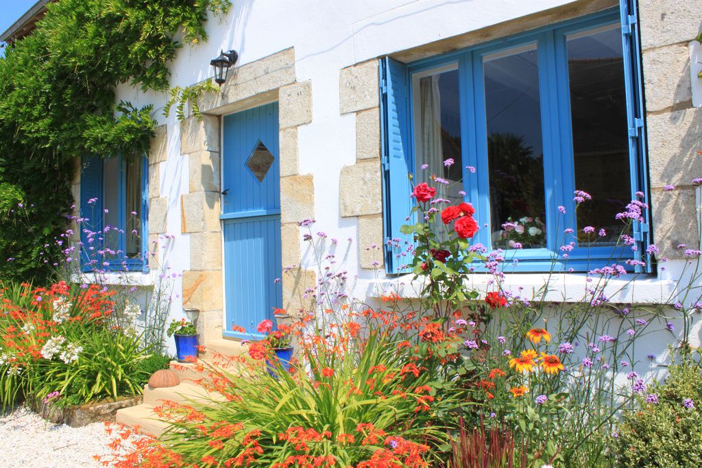 Exterior of Brittany Spa Cottages in Brittany, France with lovely bright blue door and lots of colour flora in front of the property