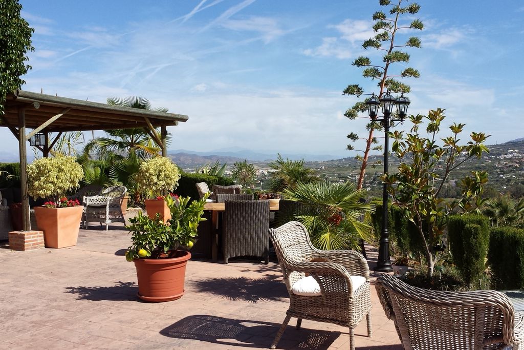 Exterior view of Casa Don Carlos, Málaga, Spain. Terrace with wicker chairs, pink tiles and view over the city