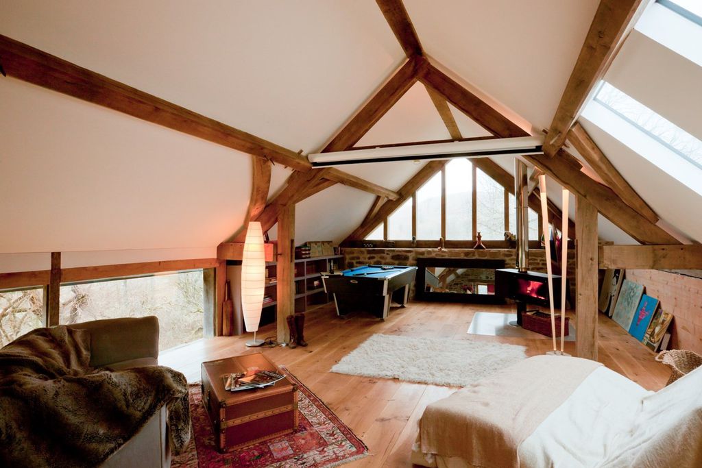 Games room and lounge area at Red Kite Barn in Powys, Wales with two comfy chairs, magazines, wood burner and pool table