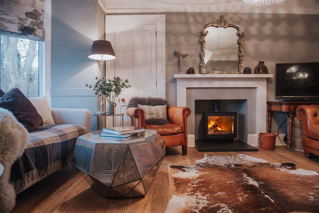 Cosy and beautifully furnished living room at No. 2 in Ballater, Aberdeenshire with tan leather chairs, fur rug and wood burner
