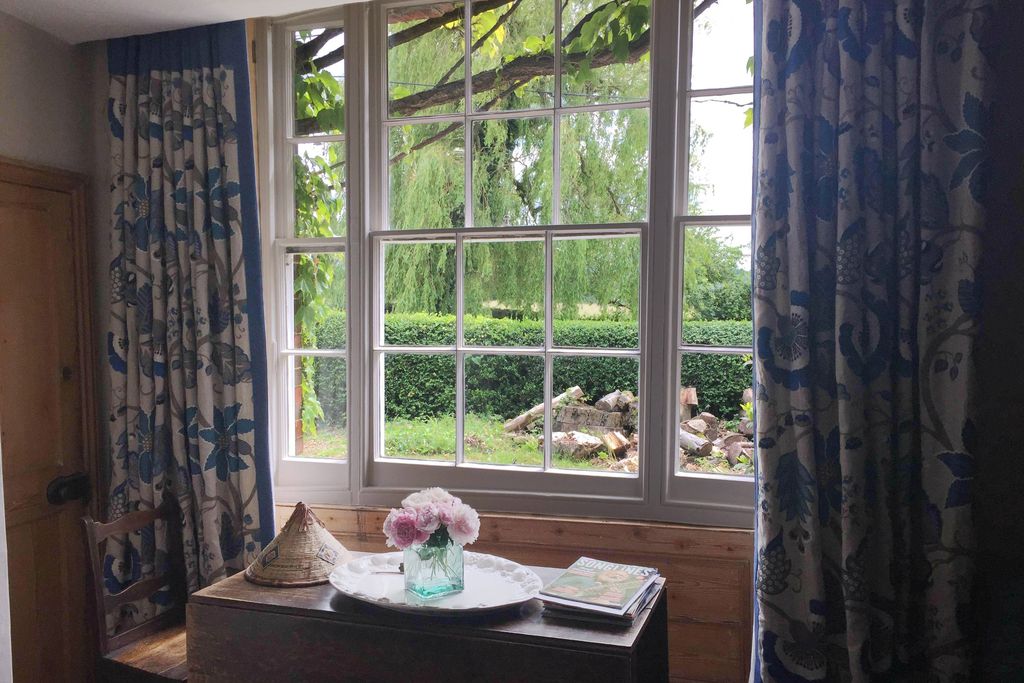 Pretty window view at Elmdon Lee with table and chair, fresh flowers and magazine pile