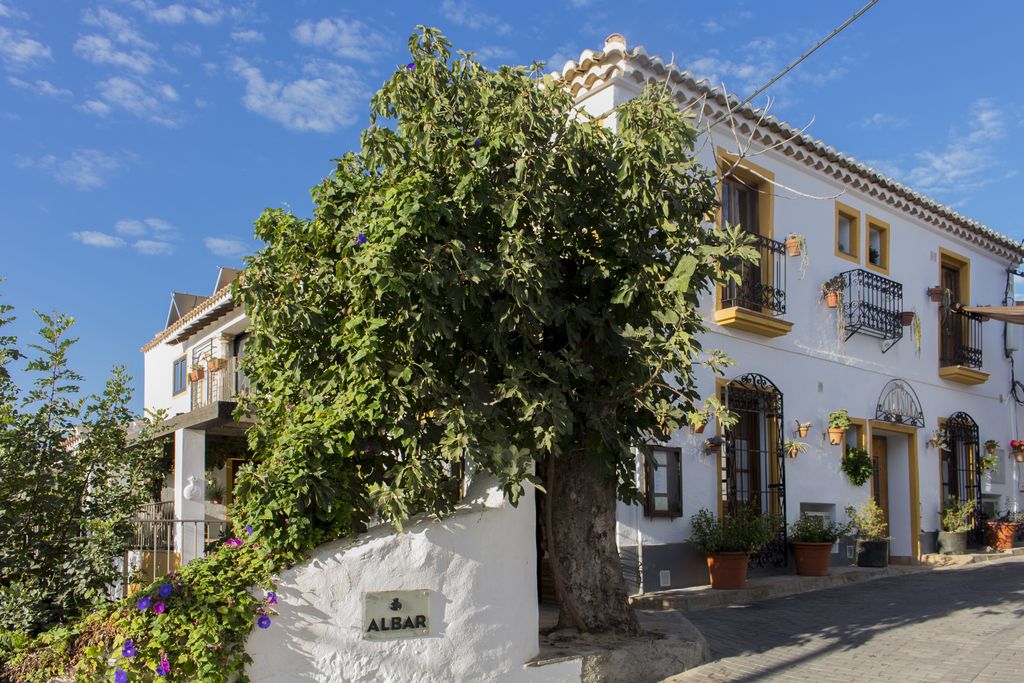 Exterior of the gorgeous Casona Granado in Almeria, Spain with white-washed walls and iron balconies, and lots of plants surrounding the entrance