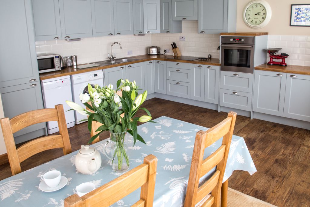 View of the spacious open-plan kitchen and dining room at The Old Barn in Exbury, Hampshire with pastel blue units
