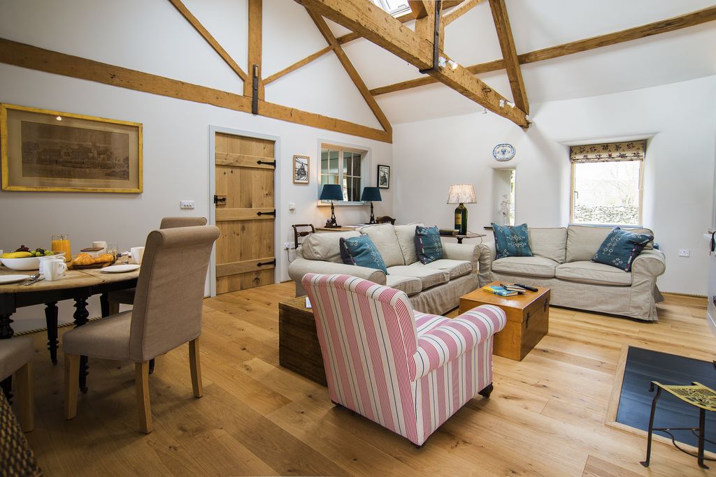 Open plan lounge and kitchen area at Y Boncyn in Gwynedd, Wales, with exposed beams and wooden flooring