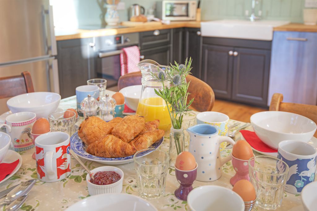 Dining table set for breakfast with freshly baked danishes, orange juice and boiled eggs