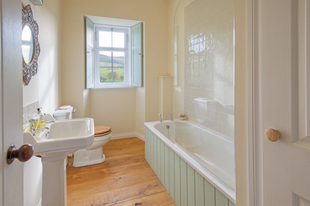 Bathroom with shower over the bath and window with traditional shutters