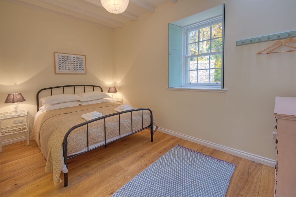 Large stylish double bedroom with a cosy bedspread and wooden floors