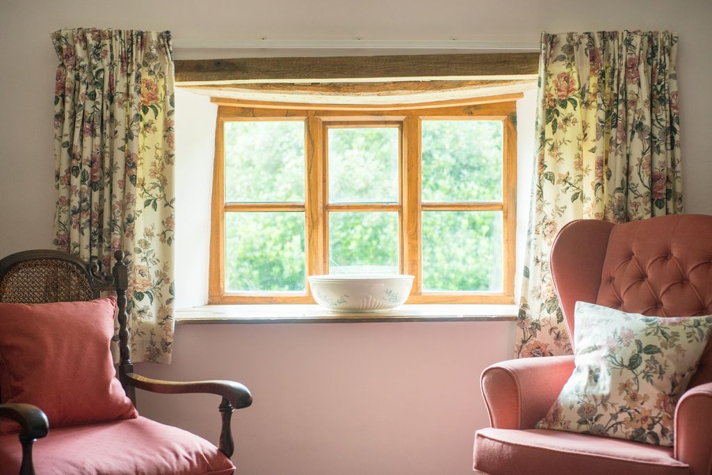 Two armchairs sitting under the bedroom window