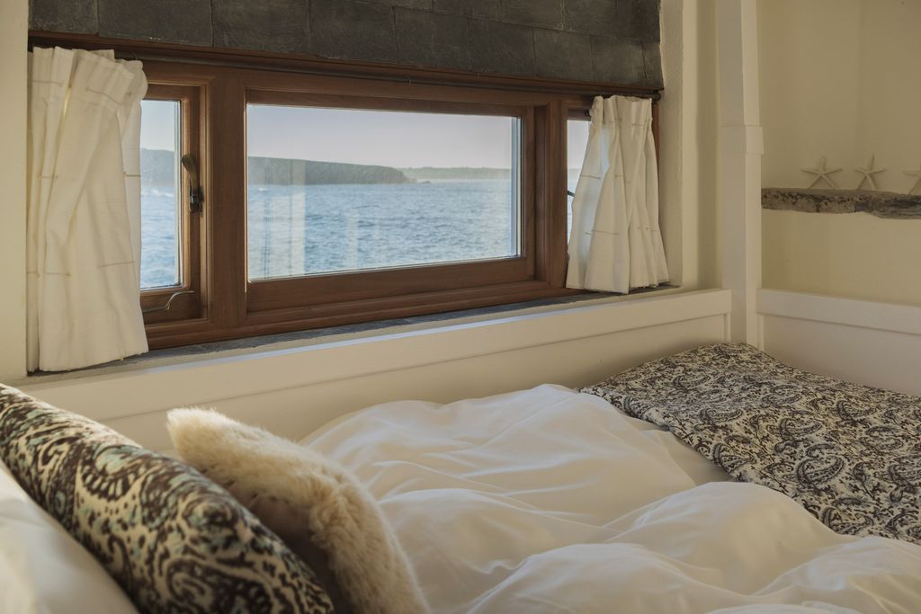 Cosy bedroom with the bed situated under the window which looks out onto sea