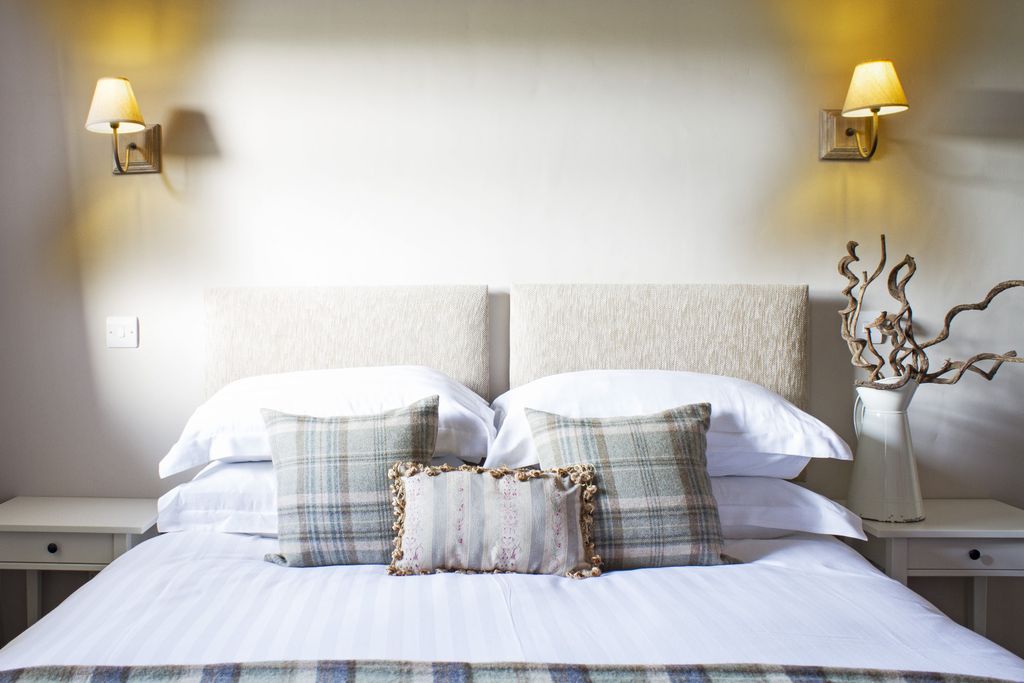 Light and airy bedroom with white linen and tartan pillows