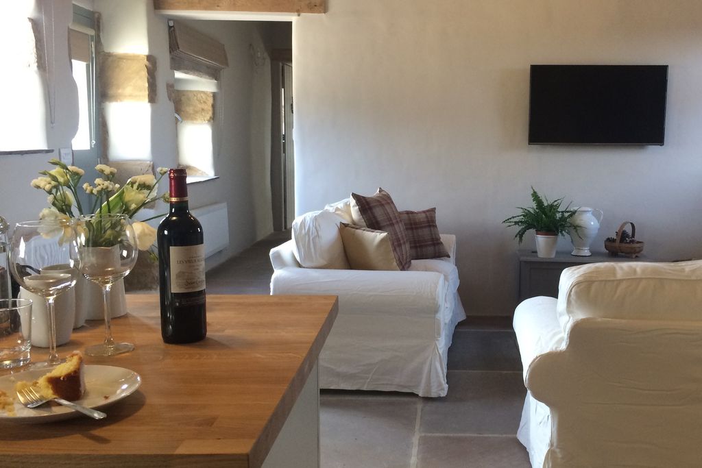 Open plan kitchen and lounge area with white sofas and original stone flooring