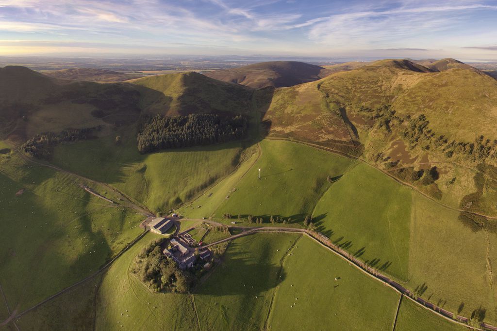 Aerial view of Steading Cottage in Penicuik in Scotland, sitting alone among miles of beautiful countryside and mountainous landscape