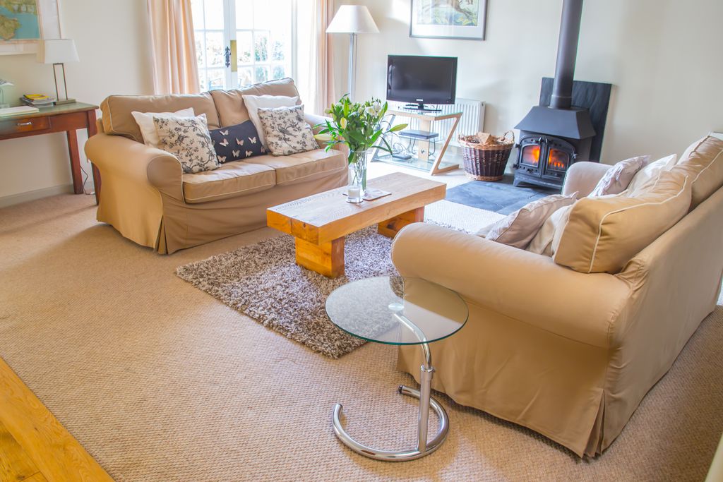 Living room at The Old Barn in Hampshire with French windows, squishy sofas and a real wood burner 
