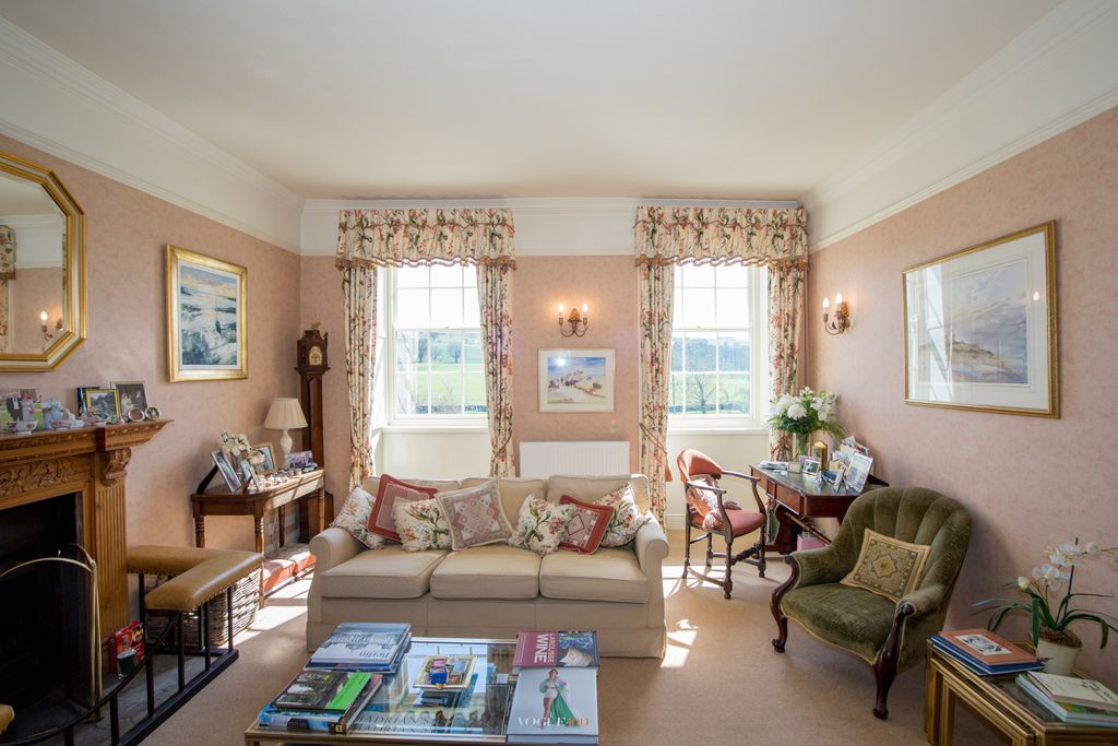 Light and sunny communal living area at Errington House with homely furnishings, open fire and lots of reading material