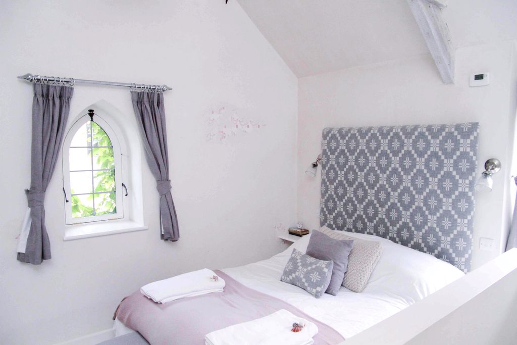 Light and fresh bedroom at The Chapel in Devon with lovely, small chapel-style window