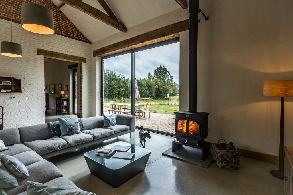 L-shaped sofa with woodburner in the living room of Old Hall Farm Barn in Norfolk 