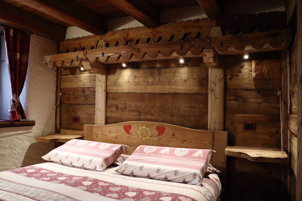 Wooden, hand-crafted bed inside of La Maison de grand Maman in Aosta Valley, Italy 