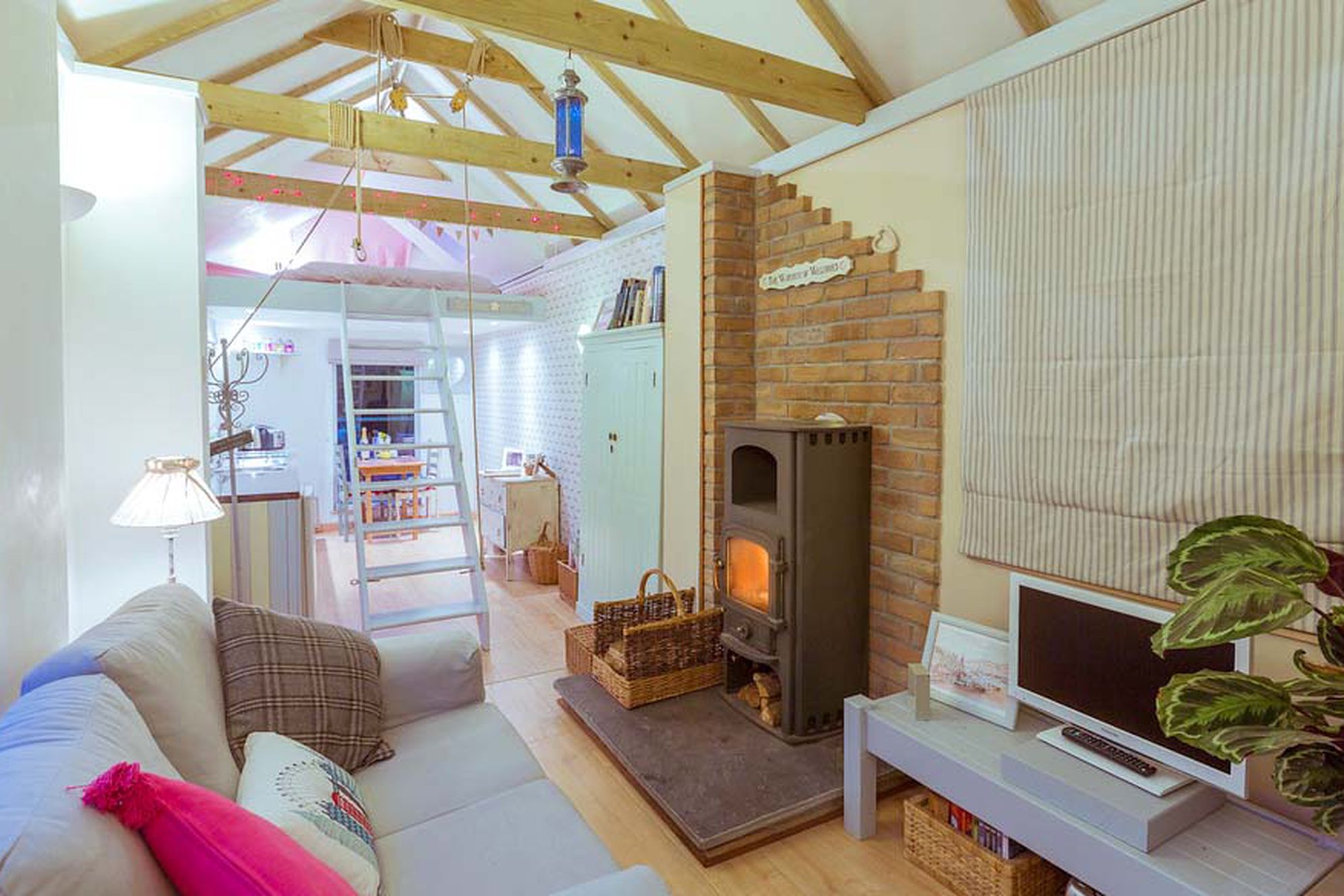 The Old Goathouse Cornwall showing the open plan lounge and kitchen with a ladder leading up to the bedroom