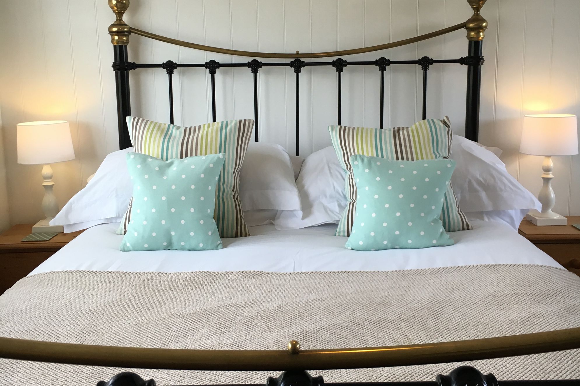Cosy double bedroom with traditional wrought iron bed and colourful cushions