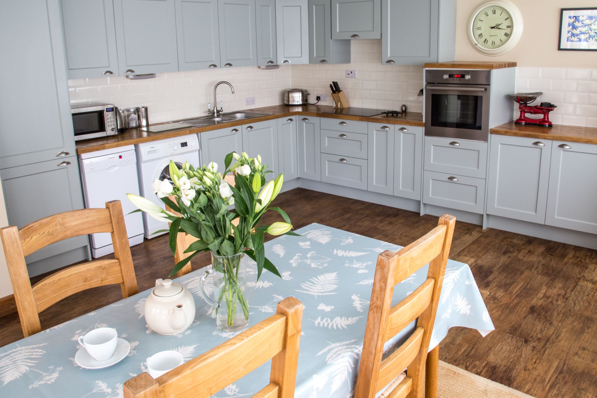 View of the spacious open-plan kitchen and dining room at The Old Barn in Exbury, Hampshire with pastel blue units
